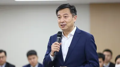 A 35-year-old manager with short dark hair, wearing a solid navy blue suit with a white shirt, standing in a press...