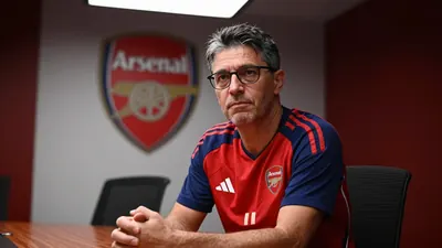A 45-year-old, anonymous, 40-year-old male Arsenal executive, dressed in the club's iconic red home kit with navy sleeves...