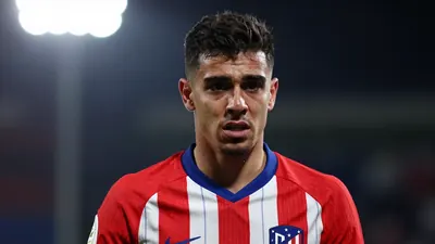 A 25-year-old, athletic, dark-haired Atletico Madrid forward, wearing a red and white kit, looking frustrated, with a...