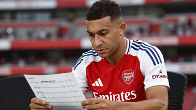 A close-up, waist-up shot of a 25-year-old, 5'9" Argentine midfielder with a strong, athletic build, wearing the Arsenal...