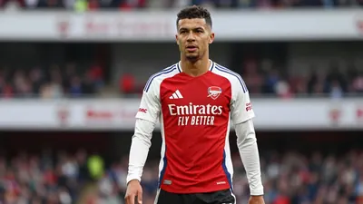 A tight waist-up shot of an anonymous Arsenal player in a red jersey with white sleeves and black shorts, with a 85mm...