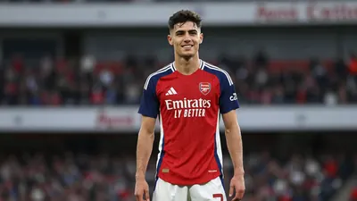 18-year-old athletic forward, lean build, waist-up, intense eyes, short dark hair, smiling confidently in Arsenal home...