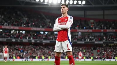A tight action crop of an anonymous Arsenal player in a white jersey with red sleeves and red socks, looking determined...